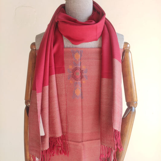 Red and pink stole with a pattern draped over a mannequin on a wooden stand.