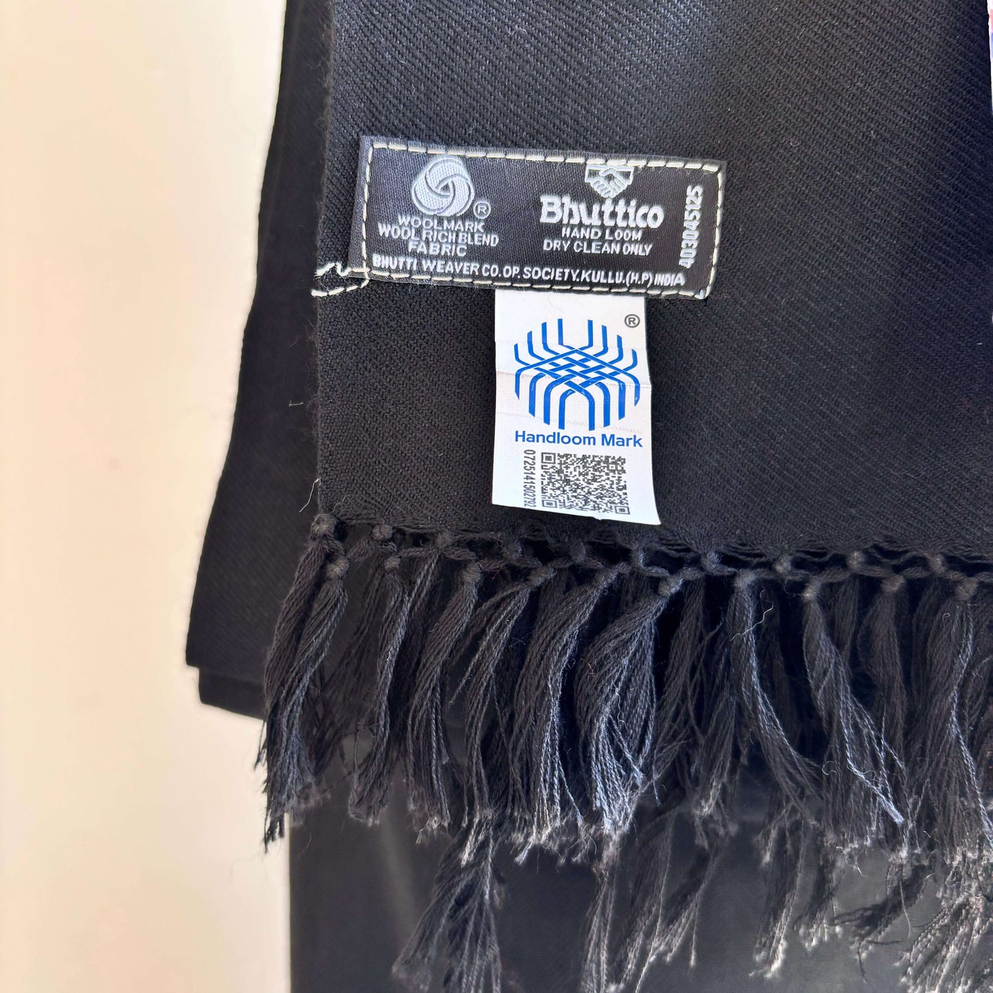 Black scarf with Bhutto label and Handloom Mark on a beige background