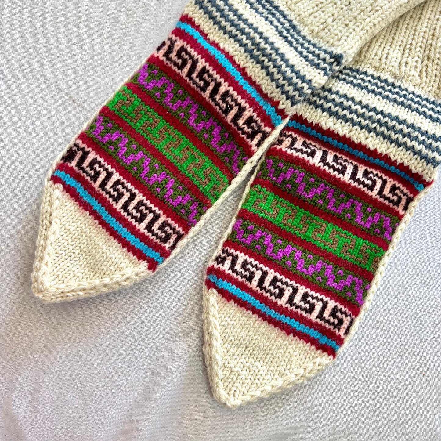Pair of woolen socks with colorful pattern made from merino wool on a light background