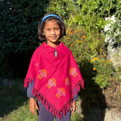 Young girl wearing aHandwoven Himachali merino wool kids poncho with tassel edges in an outdoor setting
