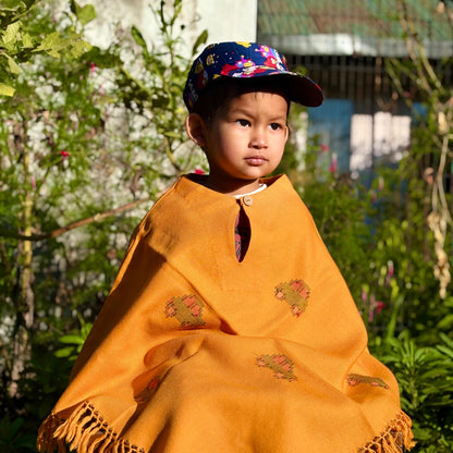 Child wearing Sunshine Car Kids Poncho in mustard yellow outdoors